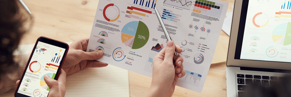 Business analyst preparing a competitive intelligence report on dual monitors