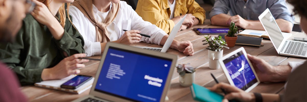 Sales team collaborating around a table with laptops and documents